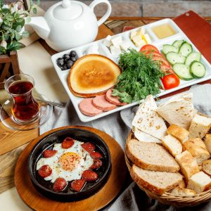 breakfast-setup-with-egg-sausage-dish-breads-vegetable-slices-cheese-honey-tea (1)
